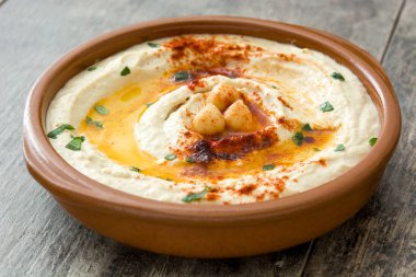 Ahşap masa üzerinde bir kapta nohut humus.