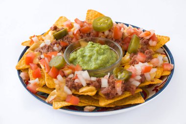 Sığır eti, guacamole, peynir sos, biber, domates ve soğan beyaz arka plan üzerinde izole plaka ile Meksika cips