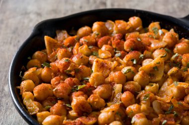 Ahşap masa üzerinde tavada kızarmış baharatlı nohut kadar kapatın