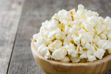 Ahşap masa arka plan üzerinde kase patlamış mısır.