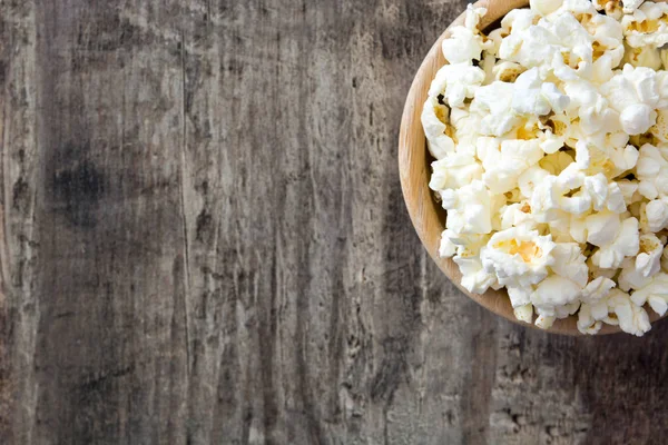 Popcorn in bowl on wooden table. Top view copyspace