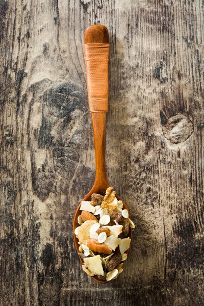 Muesli and dried fruit in wooden spoon on wooden table. Top view