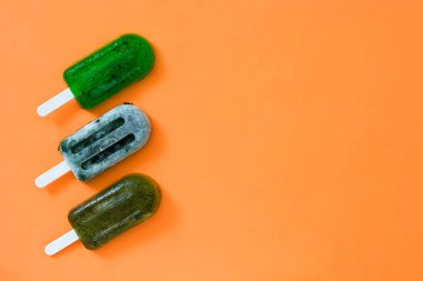 Turuncu zemin üzerine yeşil donmuş çubuklu dondurmayı. Üstten Görünüm. Boşaltmak
