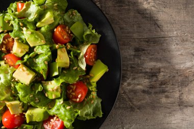 Avokado salatası, marul, domates, ahşap masadaki tohumlar. Üst görünüm. Boşluğu kopyala