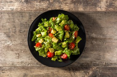 Avokado salatası, marul, domates, ahşap masadaki tohumlar. Üst görünüm