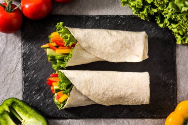 Vegetable tortilla wraps on gray stone background. Top view clipart