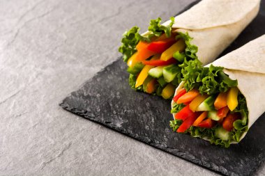 Sebzeli tortilla gri taşlı arka plana sarılır. Boşluğu kopyala