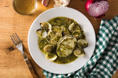 Tahta masada yeşil soslu balık ve istiridye. Tipik İspanyol tarifi..