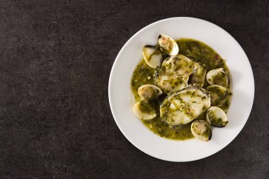 Siyah arka planda yeşil soslu istiridye ve balık. Tipik İspanyol tarifi..