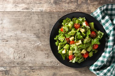 Ahşap masada avokado, marul, domates ve keten tohumlu salata. Üst Manzara. Boşluğu kopyala