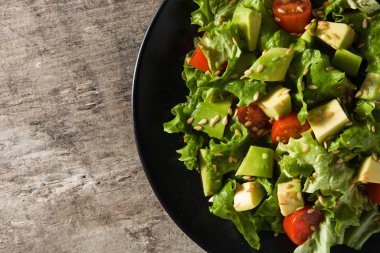 Ahşap masada avokado, marul, domates ve keten tohumlu salata. Üst Manzara. Boşluğu kopyala
