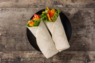 Sebzeli tortilla ambalajı ahşap masada. Üst görünüm