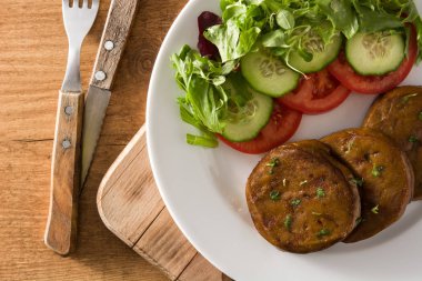 Seitan, ahşap masa manzaralı sebzelerle. Sahte et.