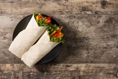 Sebzeli tortilla ahşap masaya sarılmış. Üst manzara. Boşluğu kopyala