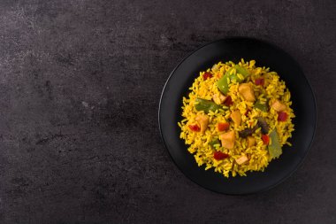 Tavuklu pilav ve siyah tabakta sebze. Boşluğu kopyala.