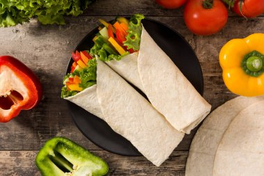 Sebzeli tortilla ambalajı ve malzemeler ahşap masada. Üst görünüm. 