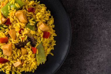 Siyah tabakta tavuk ve sebzeli kızarmış pilav ve siyah arka plan. Kapat.