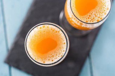 Mavi ahşap masa üzerinde kristal bardakta Bellini şampanya kokteyli.