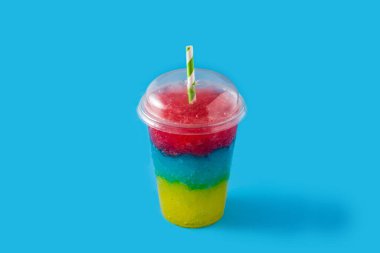Colorful slushie of differents flavors with straw on blue background clipart
