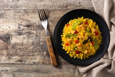 Tavuklu kızarmış pilav ve ahşap masadaki siyah tabakta sebze. Üst Manzara. Boşluğu kopyala