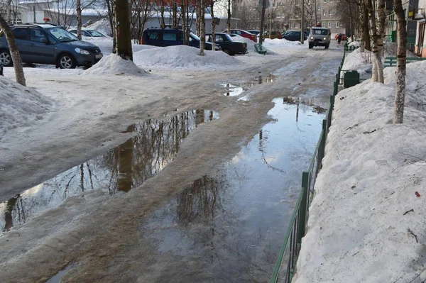 Şehrin sokaklarında eriyen su birikintileriyle yürüyün