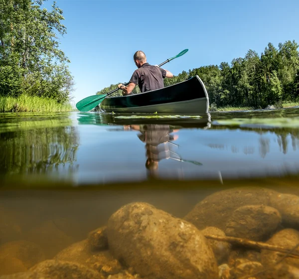 Un hombre nada en un kayak en el lago en el día de verano —  Fotos de Stock