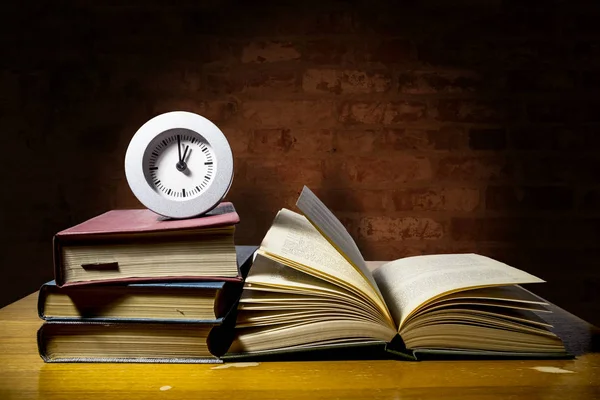 saati gösteren saat kitap yığını vardır 