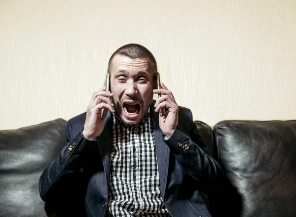 Człowiek w garniturze wiadomości emocjonalnie w dwóch smartphon — Zdjęcie stockowe