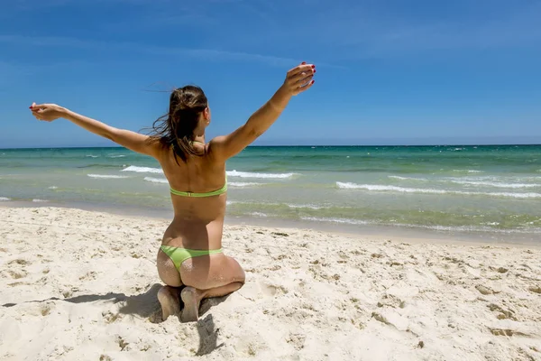 Dziewczyna w bikini, siedząc na piasku na plaży na słoneczny se — Zdjęcie stockowe