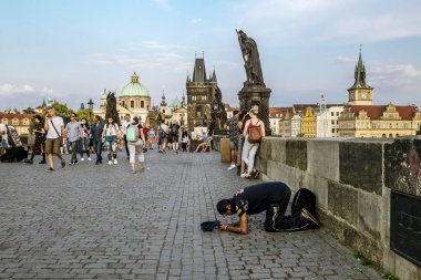 Prag 'daki Charles köprüsünde turistler ve dilenciler.
