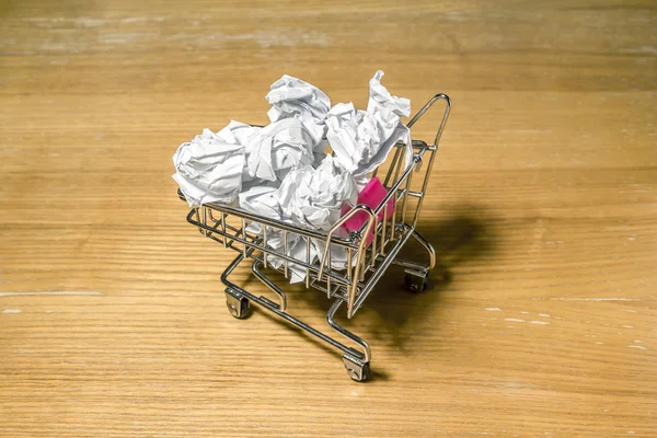 A pile of crumpled paper in a miniature grocery cart — ストック写真