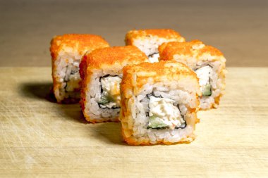 Tahta bir yüzeye düzgünce yerleştirilmiş farklı bir suşi seti.