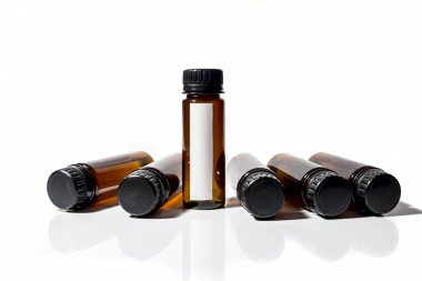 Kapaklı birkaç tıbbi test tüpü var ve beyaz arka planda yatıyorlar.