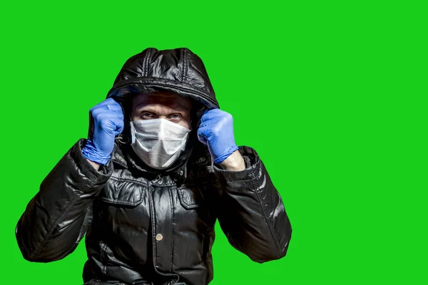 a man in a medical mask pulled the hood over his head taken in isolation on a green background