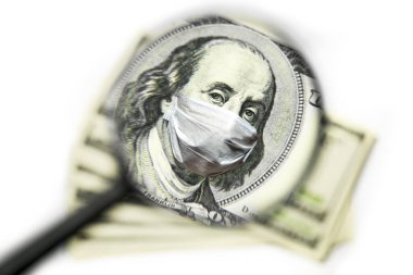 Franklin tıbbi bir maske takmış, beyaz arka plandaki büyüteçle 100 dolarlık banknotun üzerinde.