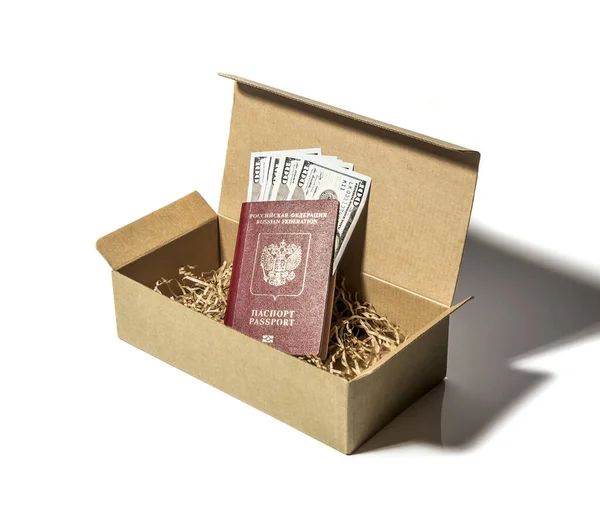ロシアの外国パスポートに囲まれた百ドル札は白い背景の段ボール箱に入っています — ストック写真