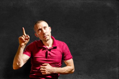 İşaret parmağını havaya kaldırmış, tahtaya karşı parlak bir fikirle gelen genç bir adam.