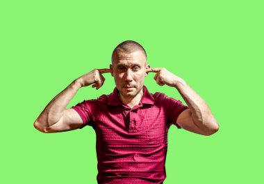 Adam yeşil arka planda parmaklarını kulaklarına koydu.