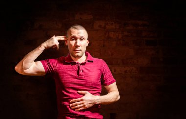 Adam elini kafasına dayadı parmaklarıyla tuğla duvara dayalı bir silah gibi.