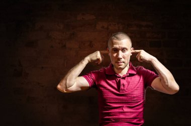 Adam parmaklarıyla kulaklarını duvara dayadı.