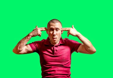 Adam yeşil bir arka planda parmakları silah şeklinde olan ellerini kafasına koydu.