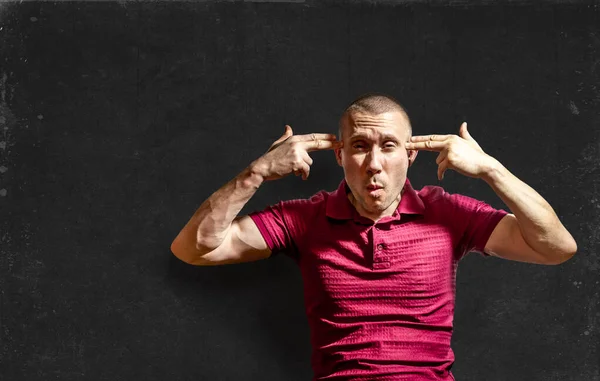 Adam ellerini başının üstüne koydu. Parmakları silah şeklindeydi. Arkasında karatahta vardı.