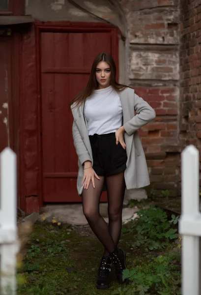 Young girl stands on the background of a city street. Girl in a gray coat. A series of photos with a brunette — Stock Photo, Image