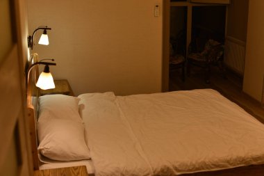 Otel odasında bir yatak. Yatak ve yastıklar. Ahşap bir yatak başlığı, iki dolap ve yer lambası olan bir yatak..