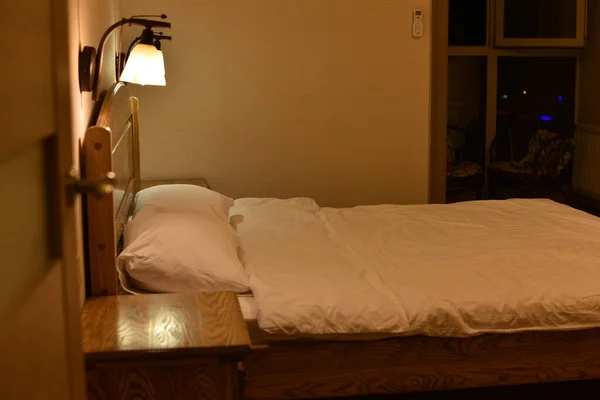 Cama en una habitación de hotel. Cama y almohadas. Una cama con cabecero de madera y dos armarios y lámparas de pie . — Foto de Stock