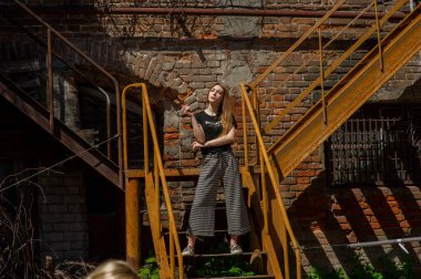 Metal merdiven ve arar basamaklarda yalan sarışın güzel kız