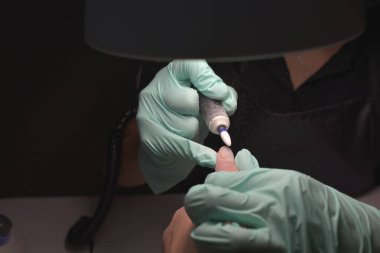 Kadın elleri güzellik salonunda manikür yaptırıyor. Tırnak törpüleme. Yaklaş, seçici odaklanma.