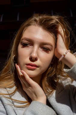 Gri ceketli şık genç güzel kız kameraya bakar ve şehrin arka planına karşı hafifçe gülümser.