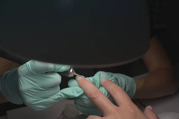 Mains de femme recevant une manucure dans un salon de beauté. Classement des ongles. Gros plan, focus sélectif. — Photo