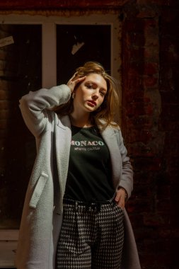 Gri ceketli şık genç güzel kız kameraya bakar ve şehrin arka planına karşı hafifçe gülümser.